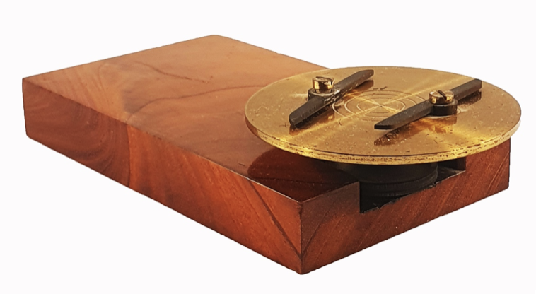 A wooden block with a circular object on it
Description automatically generated